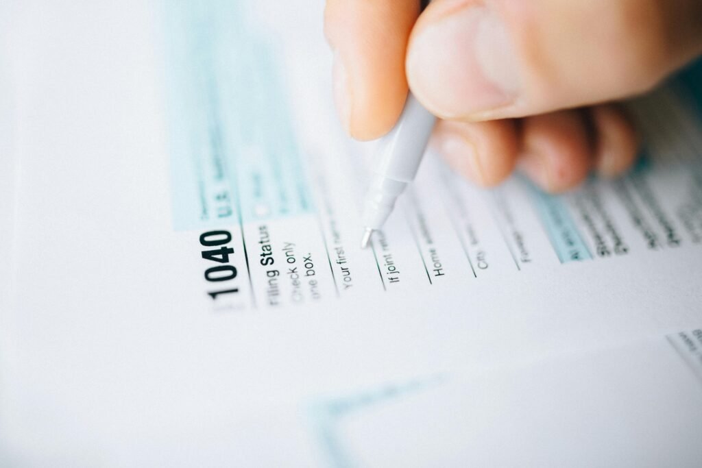 Close-up of a hand using a pen to fill out a tax form 1040, focusing on details.